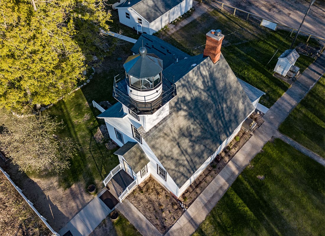 About Our Agency - View from Above Looking Down at a Historical Lighthouse at Sunset in Michigan Surrounded by Green Grass
